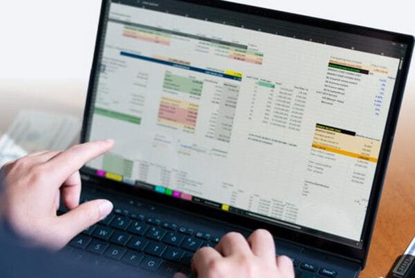 telecom-cost-optimization - Marinum Consulting Person using a laptop to view a large multi-column dashboard with charts and tables.