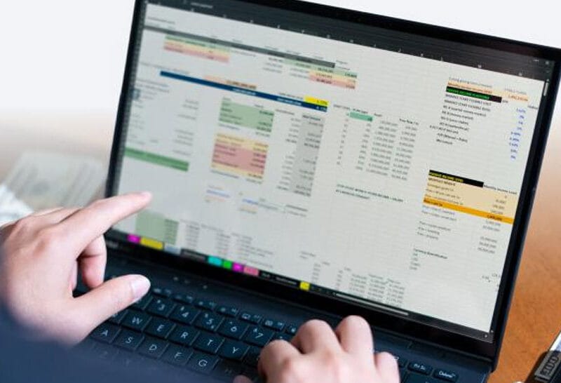 Person using a laptop to view a large multi-column dashboard with charts and tables.